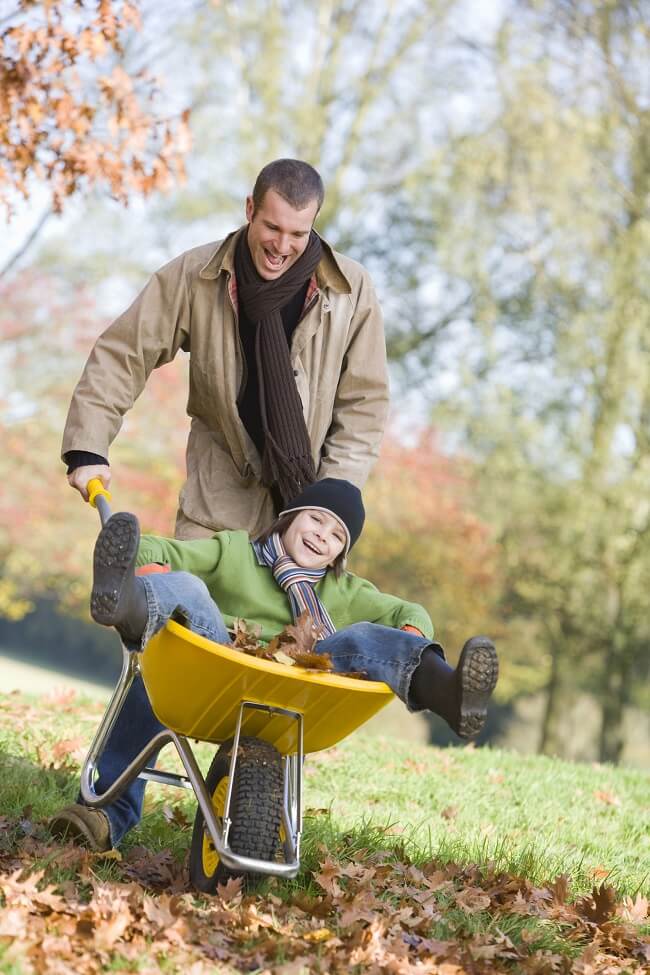 A picture of a father and his son playing on fall leaves